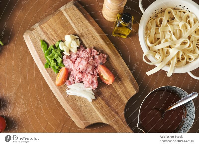 Pasta and ingredients for sauce on table bolognese pasta prepare meat pepper garlic tomato onion cut chop food vegetable mince cook mediterranean italian