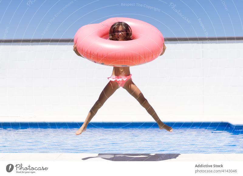 Happy kid having fun in swimming pool summer happy inflatable cheerful enjoy vacation girl holiday water excited ring pink resort recreation jump rest lifestyle