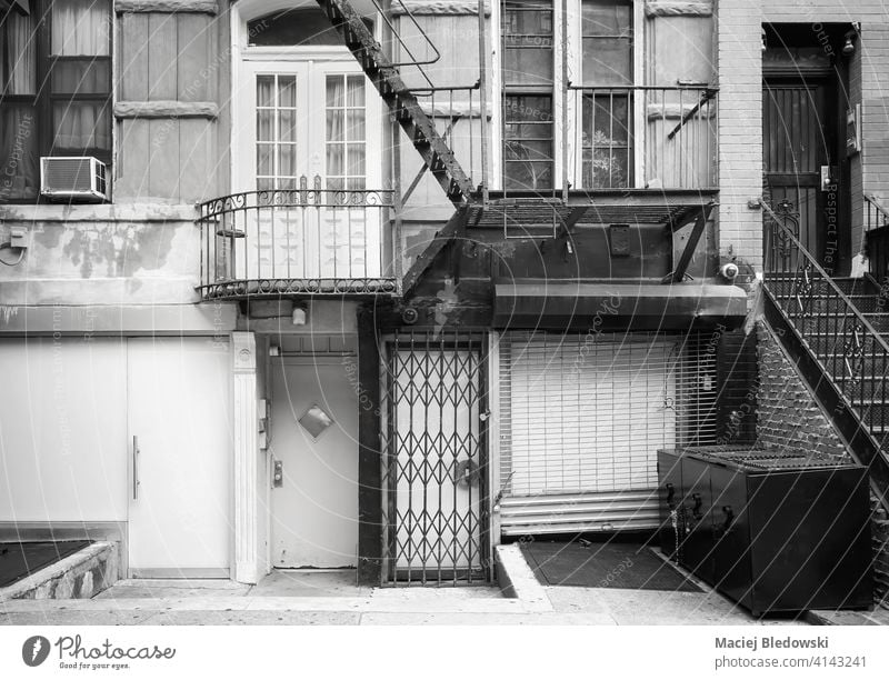 Black and white picture of old building facade with iron fire escape, New York City, USA. black and white street city townhouse apartment architecture stairs