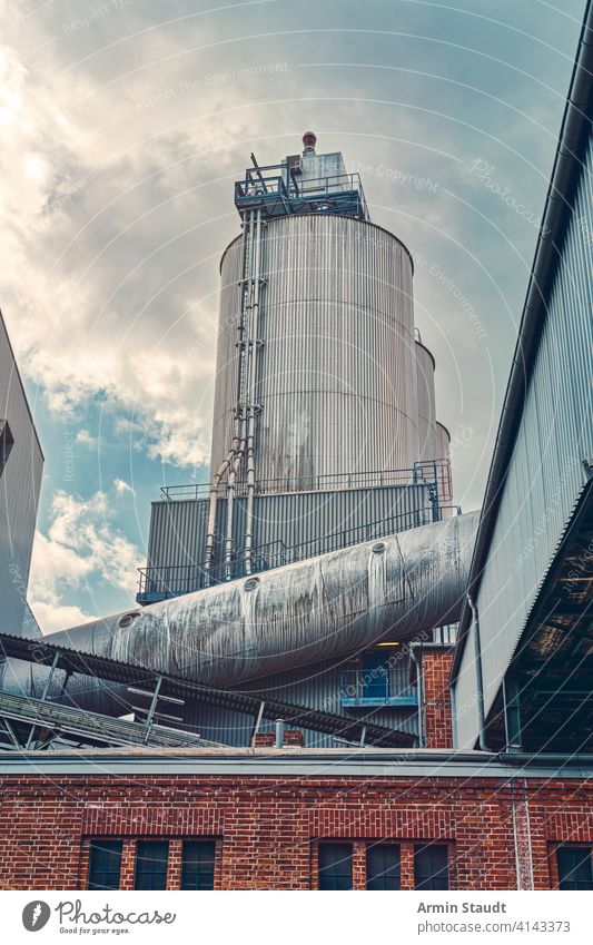 three silos and a large pipe of a factory with dramatic sky architecture building business cloudscape construction energy facility hdr industrial industry