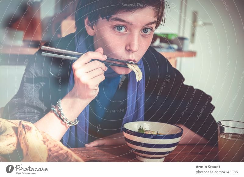 boy is eating asian food with chopsticks banana beautiful bowl casual caucasian confident delicious dinner drink fruit healthy home kitchen lifestyle looking