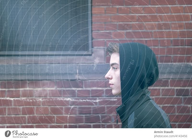 portrait of a young man in profile with hoodie beautiful boy brick casual caucasian confident cool going handsome image lifestyle looking male model mysterious