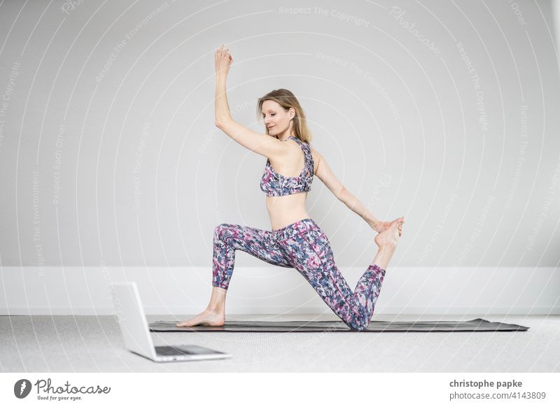 Woman doing yoga at home with laptop Yoga Online Notebook Digital Lifestyle Sports Athletic relaxation Mat Sit Blonde Computer Internet Leisure and hobbies
