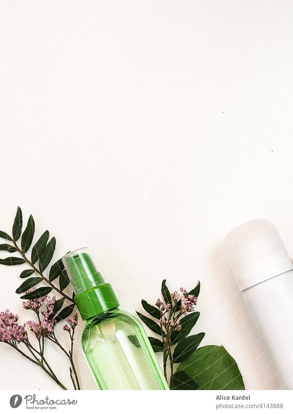 Cosmetic products for body care lie on a white background with branches of wild flowers and twigs with leaves. View from above Cosmetics cosmetic products Spray