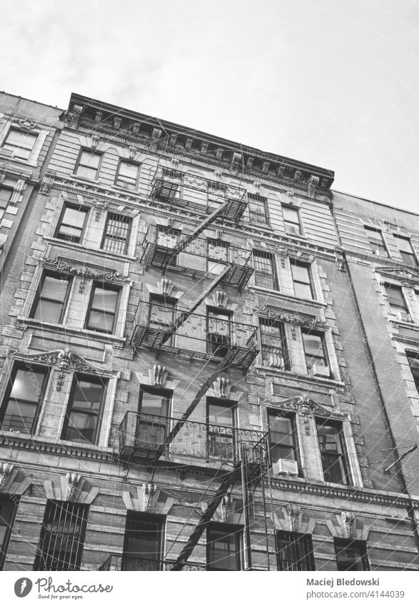 Black and white picture of old building with iron fire escape, New York City, USA. city wall townhouse black home apartment architecture stairs facade NYC