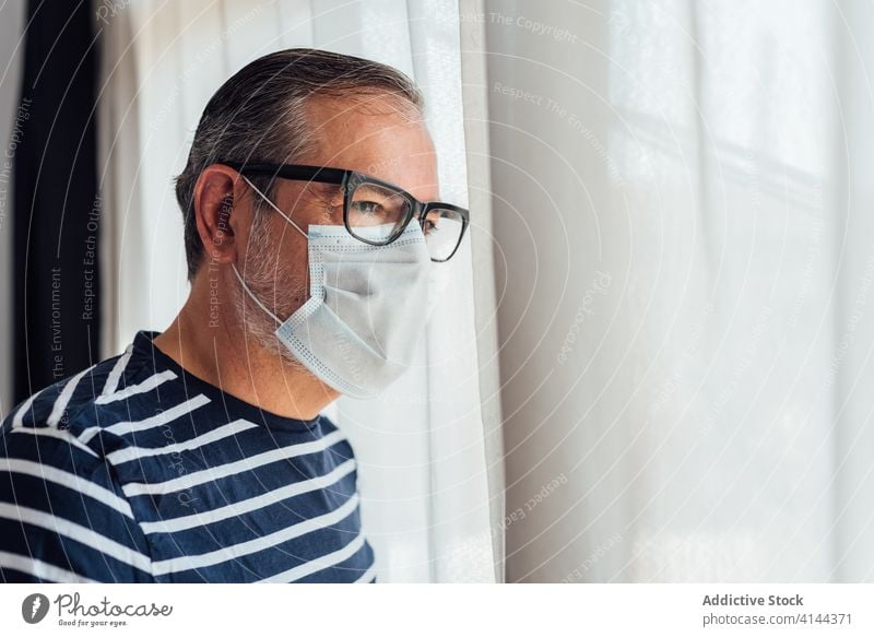 Bearded guy with respirator looking out the windows man balcony morning home apartment male beard lifestyle tranquil serene peaceful side view looking away