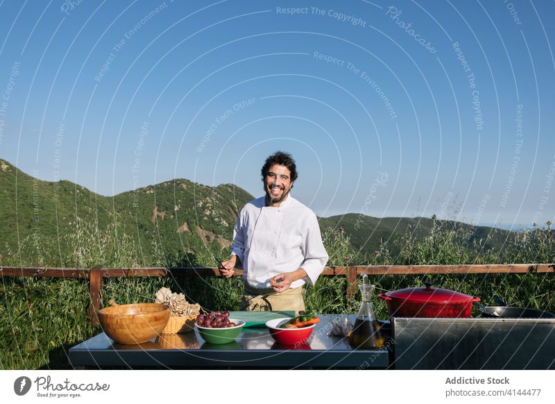 Happy professional cook preparing food in the kitchen during in nature man dish skillet mountain picturesque chef prepare cuisine delicious meal male adult