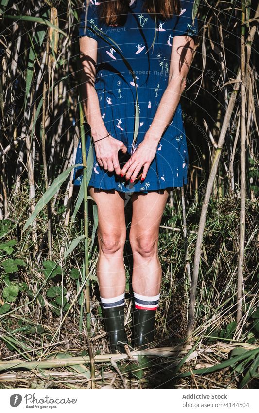 Crop woman in rubber boots in field countryside enjoy sun summer nature dress female freedom blue serene stand carefree grass rural tranquil idyllic peaceful