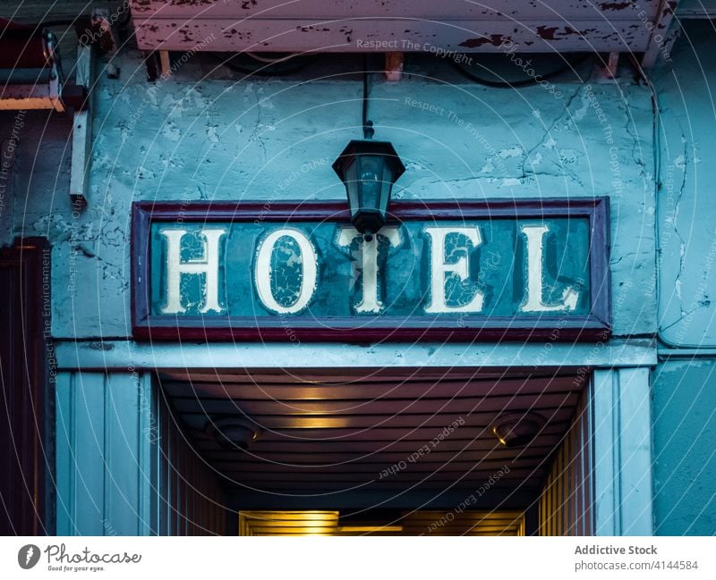 Hotel signboard placed above shabby rural entrance hotel blue rectangular building indicate weathered door panel lamp cozy old message text direction