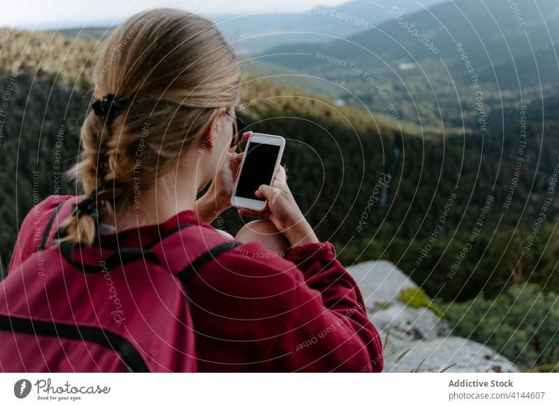 Female backpacker using smartphone while resting on mountain top woman hike travel activity trekking browsing check forest stone young nature adventure spain