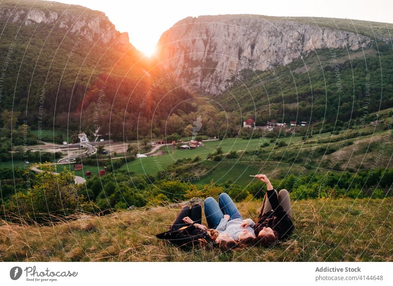 Friends lying on grass in mountainous area friend selfie together relax sunset smartphone using friendly company transylvania romania saint george device