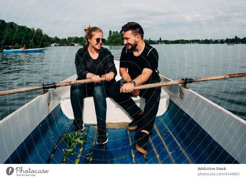 Cheerful couple rowing boat together on picturesque lake pond toothy smile cheerful nature beautiful relationship carefree activity content peaceful calm relax