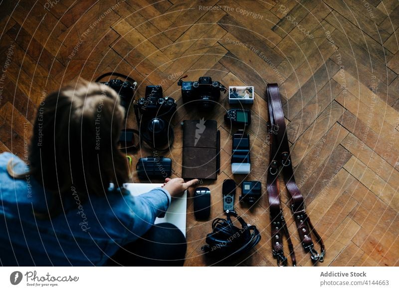 Unrecognizable photographer arranging equipment on floor woman photography arrange home parquet shabby hobby female gear cozy apartment room weathered prepare