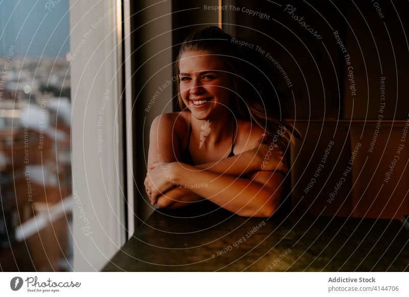 Young happy woman enjoying cityscape from cafe rooftop cheerful window evening smile madrid sunset cozy urban spain glass wall comfort relax restaurant