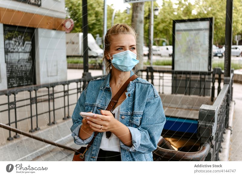 Young woman in mask with smartphone going upstairs on street city subway using urban coronavirus new normal lifestyle pandemic covid protect prevent covid19