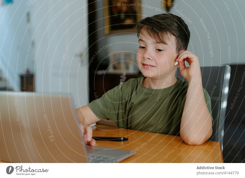 Focused kid using laptop at home boy typing table internet device gadget browsing online connection child little casual childhood smart digital concentrate