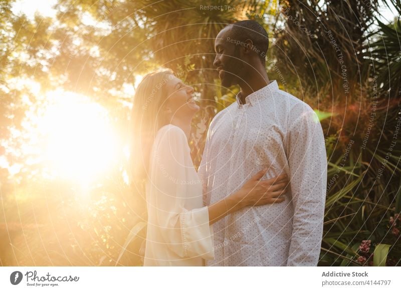 Romantic diverse couple hugging passionately in the evening garden tender romantic content sunset love affection embrace bonding modern casual intimate nature