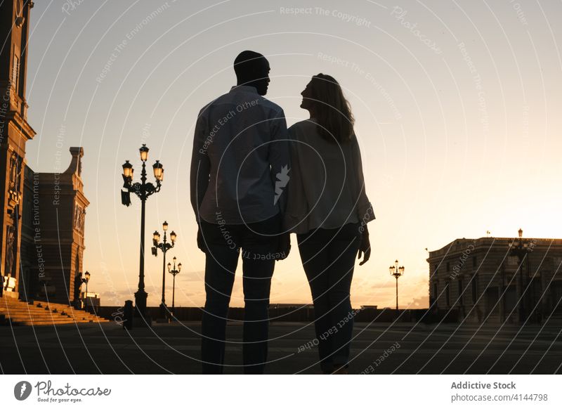 Romantic multiethnic couple holding hands and strolling along city street walk romantic carefree relationship fondness harmony affection casual spain madrid