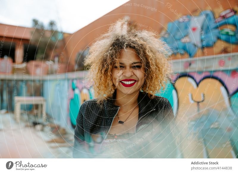 Positive black woman in city millennial urban graffiti outfit afro cheerful generation style female ethnic african american hairstyle happy street contemporary