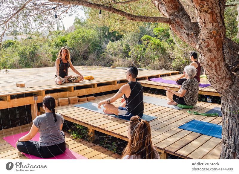 Group of people sitting in Lotus pose during yoga lesson with instructor padmasana lotus pose garden wellness harmony practice together vitality wellbeing