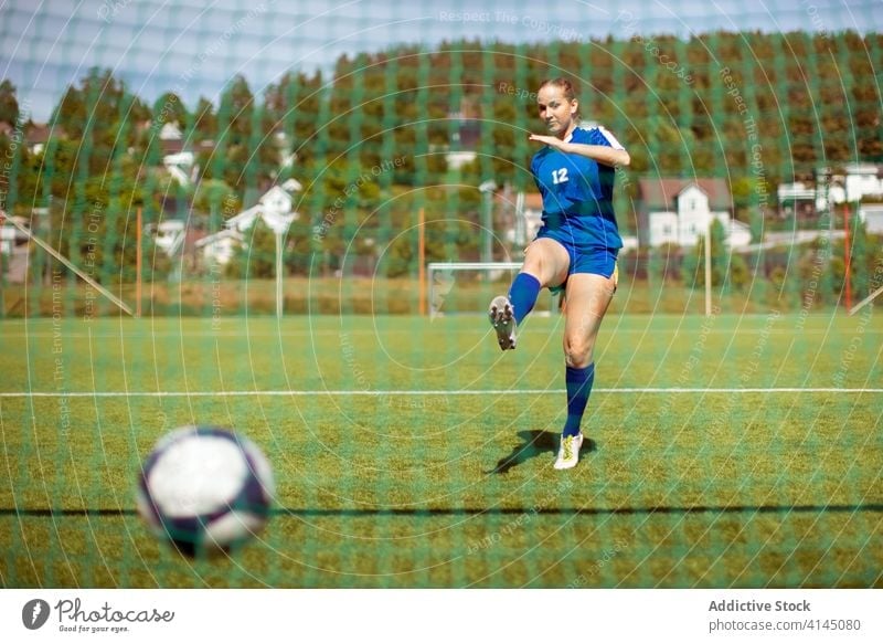 Sportswoman kicking ball into goal sportswoman football field game professional training female uniform grass soccer activity athlete sportswear score