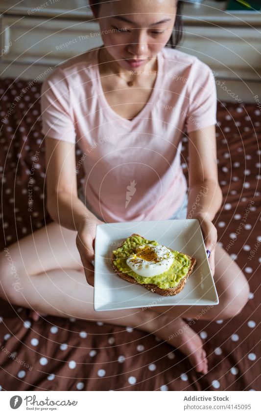 Asian woman with delicious breakfast on bed avocado toast egg natural diet healthy morning female ethnic asian pajama soft plate fresh meal poached snack yummy