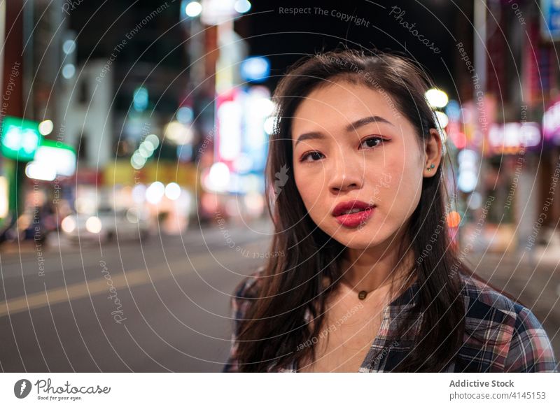 Positive ethnic woman walking on night street in city happy smile cheerful young modern urban road cross millennial asian female lifestyle casual joy glad