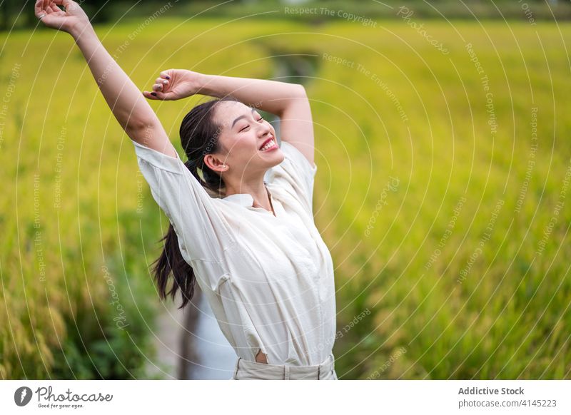 Carefree woman in green field carefree enjoy freedom summer nature rice smile tranquil female asian ethnic happy rest optimist positive glad stand relax lady