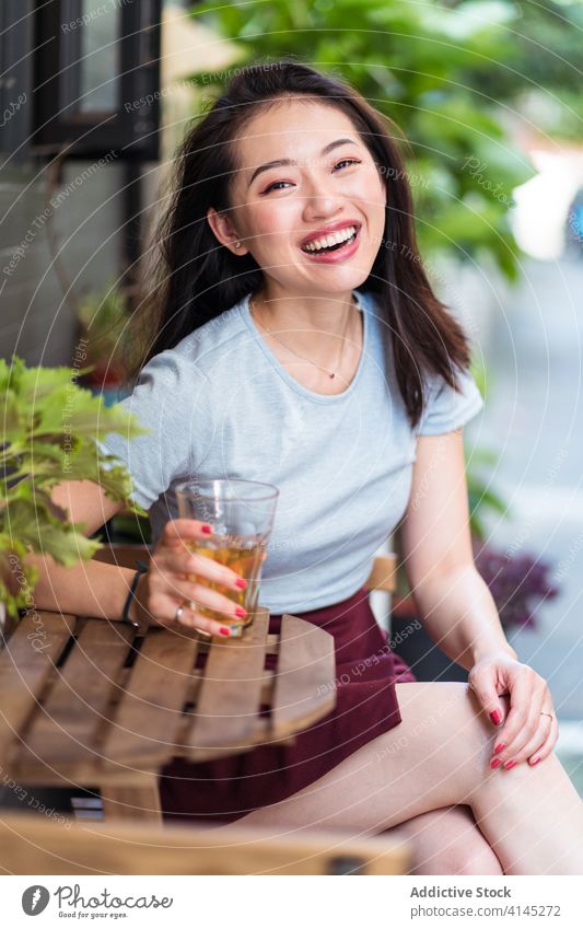Relaxed ethnic woman in cafeteria drink weekend enjoy relax counter beverage refreshment female asian rest young sit cheerful glass lady charming smile delight