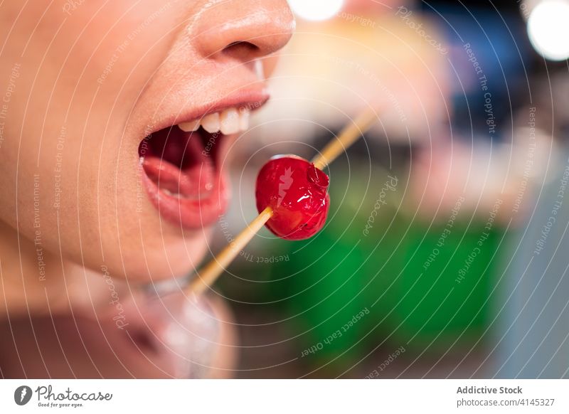Anonymous woman eating sweet tomato in city night market street food berry cherry sugar coat female zhubei taiwan wooden stick tasty oriental delicious content