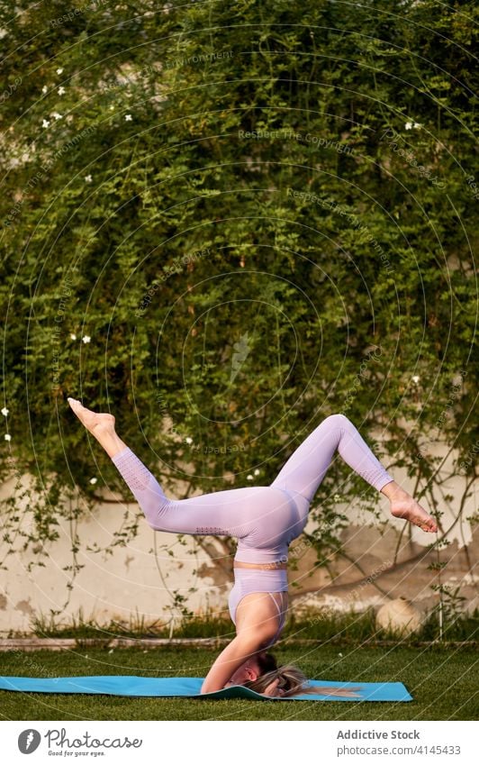 Unrecognizable flexible woman doing Supported Handstand with Splits on mat practice yoga balance barefoot health care well being harmony stress relief fit relax
