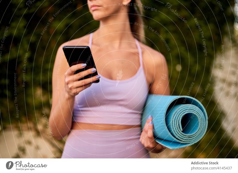Dreamy woman with smartphone and yoga mat contemplating nature contemplate health care well being sportswear harmony using device gadget cellphone fit online