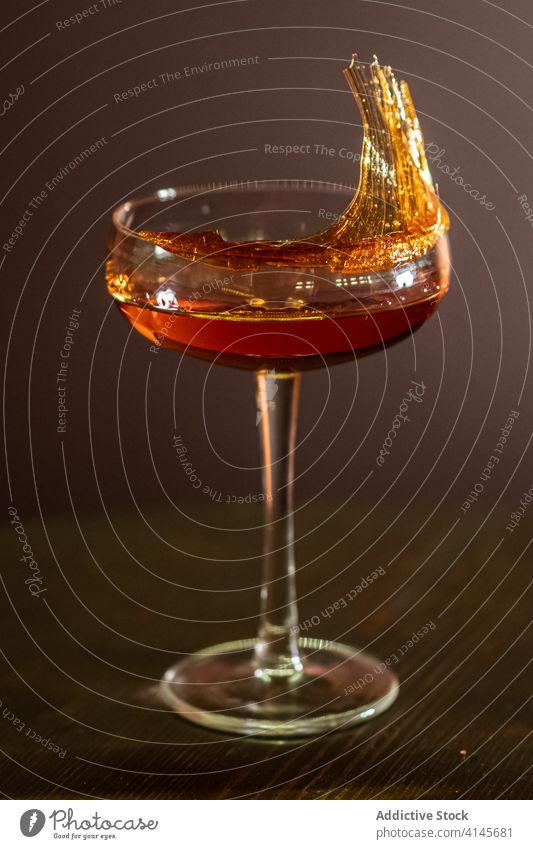 Glass of alcohol drink in bar cocktail glass table beverage sugar spun decoration liquid booze wooden shiny celebrate event occasion pub party liquor delicious