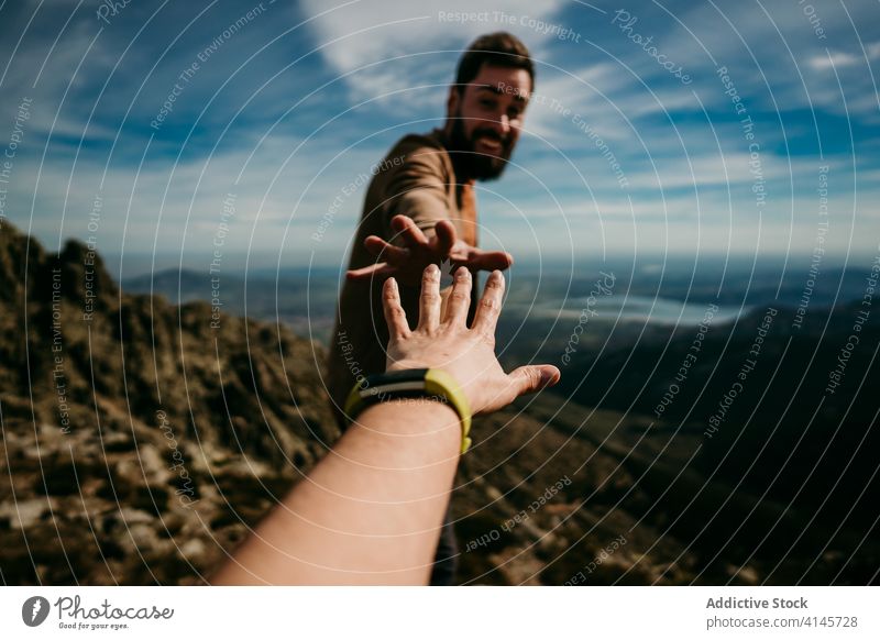 Crop traveler reaching man in mountains hiker gesture outstretch countryside puerto de la morcuera spain nature adventure journey male freedom tourism vacation