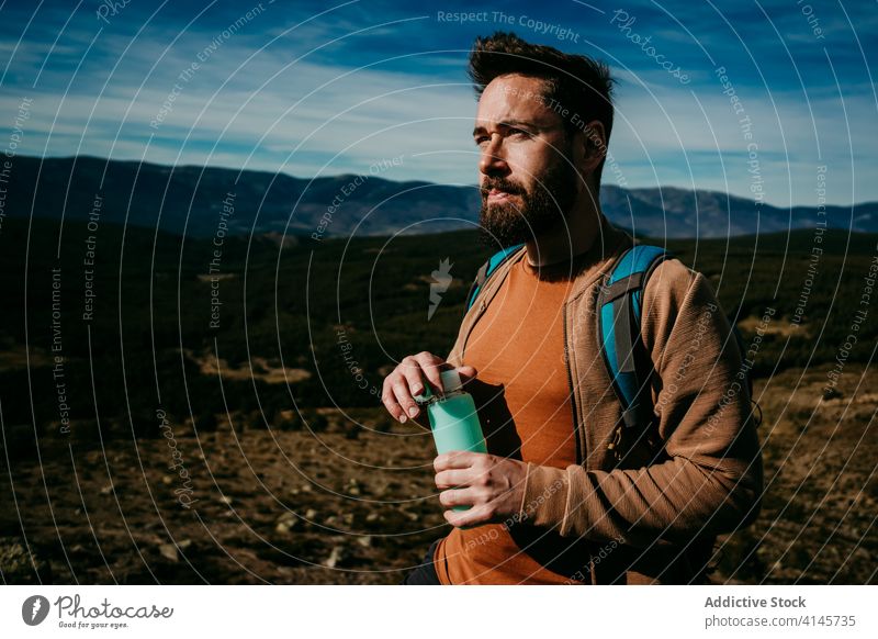 Male hiker with bottle of water in mountains man rest trip sky puerto de la morcuera thirst spain hydrate male stone journey nature beverage stand rock