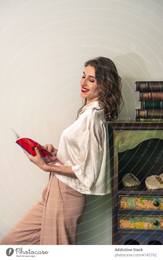 Young woman with book standing near vintage furniture read retro style happy smile young positive female relax hobby rest story home lifestyle leisure