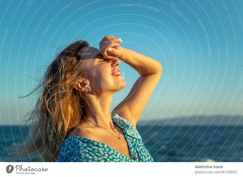 Smiling young female tourist recreating against calm ocean during sunset woman recreation seashore eyes closed enjoy happy smile traveler summer vacation
