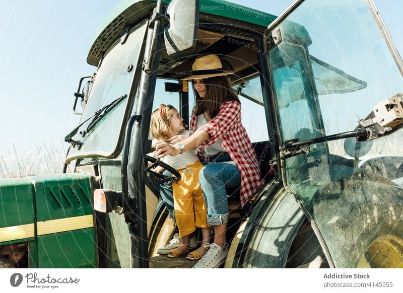 Happy woman embracing little child sitting in tractor in countryside mother embrace daughter childcare affection bonding spend time motherhood harmony together