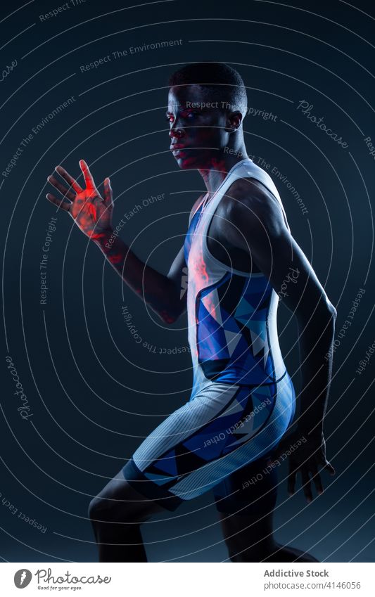 Muscular male runner in studio with neon light man athlete sportsman determine confident active physical young black african american ethnic active wear