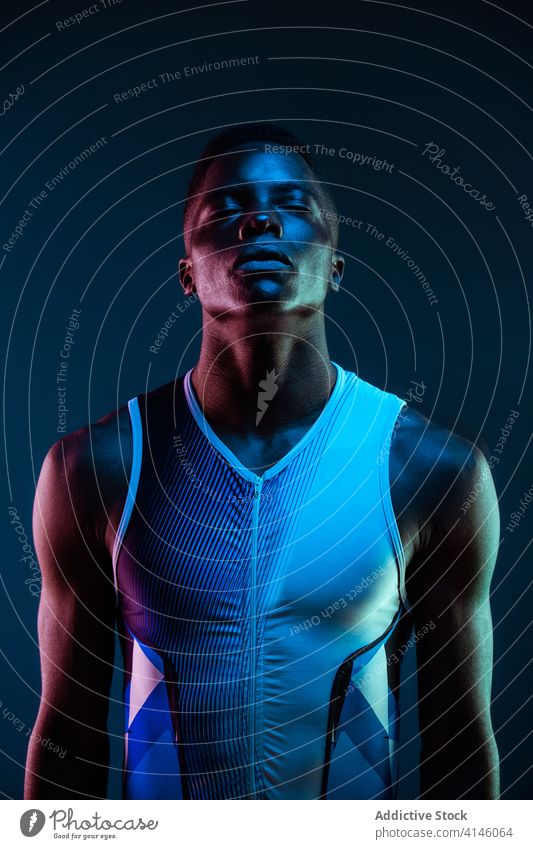 Strong ethnic sportsman with eyes closed athlete confident serious concentrate brutal competitive determine neon challenge blue active physical young black