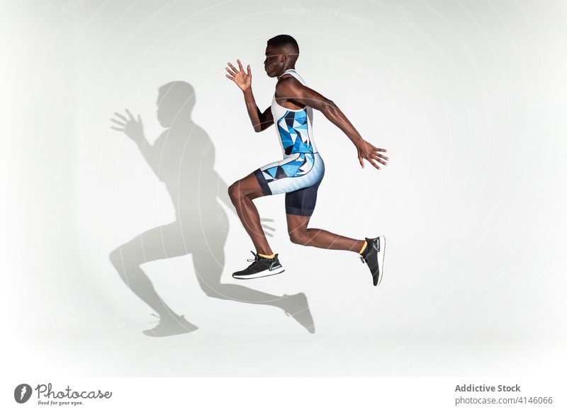 Running black sportsman in purple studio runner athlete jump speed energy sprint determine power confident active physical neon african american ethnic male