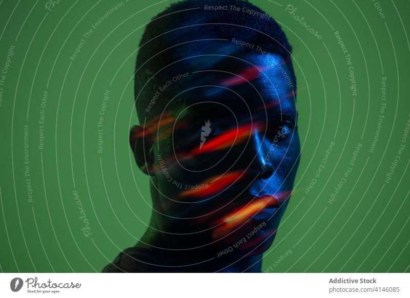 Young black man with neon illumination on face confident serious young modern creative colorful portrait light african american ethnic male human face