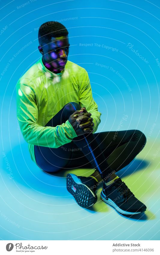 Ethnic sportsman in trendy active wear in studio athlete sportswear tracksuit outfit fashion runner sprinter jogger neon young black african american ethnic