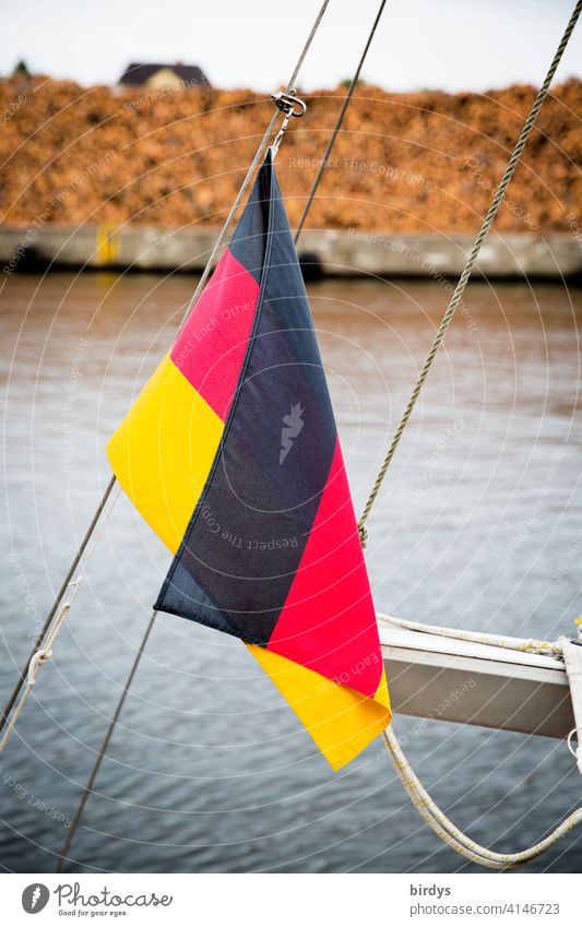 German flag on a boat in the harbour, lumber yard in the background Germany Ensign Slack slack Water Long log store Harbour tree trunks Bark-beetle coniferous