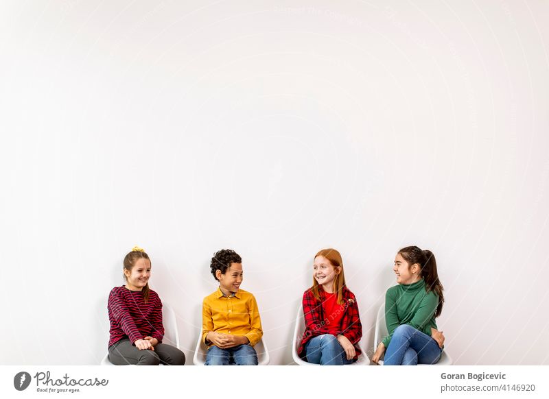 Portrait of cute little kids in jeans  sitting in chairs against white wall adorable boy casual caucasian child childhood children clothes denim expression