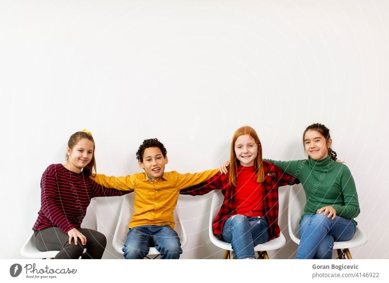 Portrait of cute little kids in jeans  sitting in chairs against white wall adorable boy casual caucasian child childhood children clothes denim expression