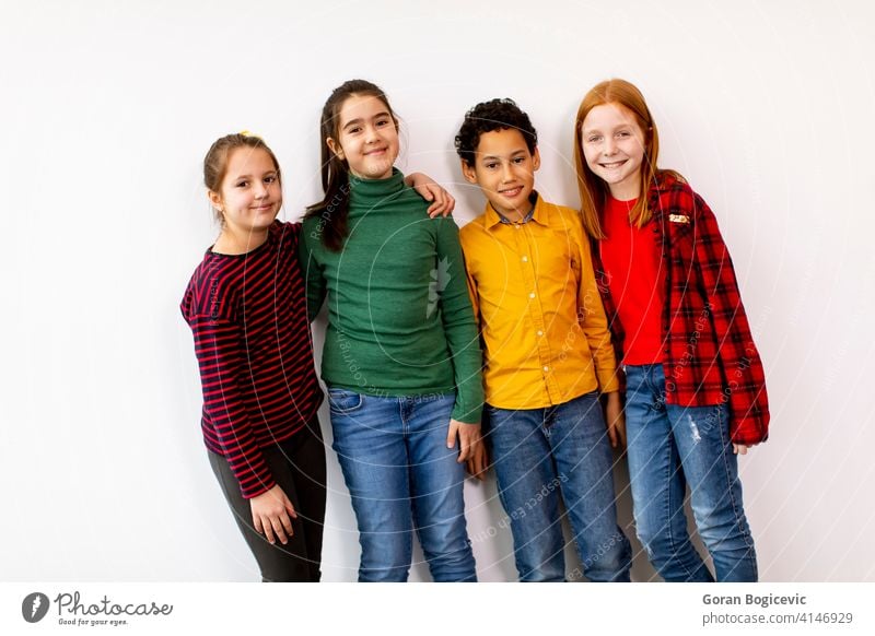 Portrait of cute little kids in jeans  looking at camera and smiling, standing against white wall caucasian boy school girl female childhood children casual
