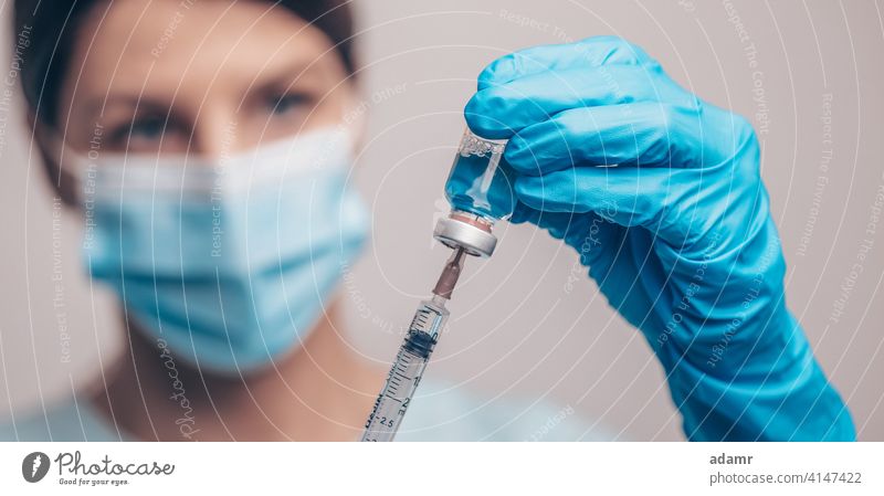 Doctor in protective gloves and mask holding glass vial with injection liquid. Vaccination against influenza and coronavirus. vaccine medicine vaccination dose