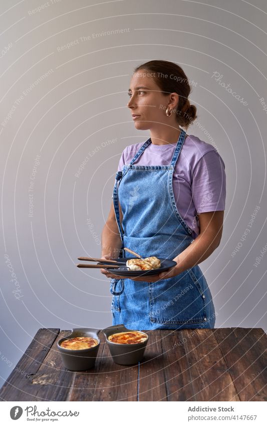 Woman with portions of creme brulee on plate dessert delicious woman sugar cook homemade tasty baked female sweet pastry apron food gourmet meal cuisine lady