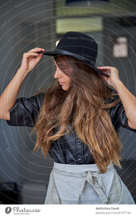 Confident young woman in trendy outfit confident style hat portrait modern long hair thoughtful female fashion urban elegant contemporary smile accessory cloth